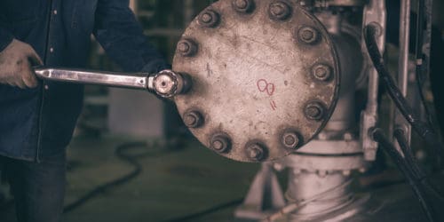 A manual torque wrench being applied in an industrial setting.